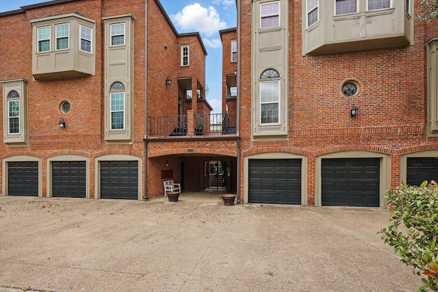 multi unit property with a garage, brick siding, and a balcony