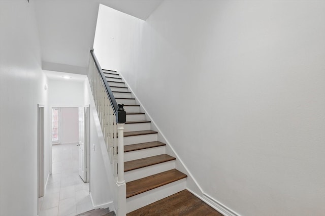 staircase with baseboards and a towering ceiling