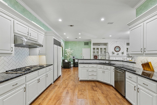 kitchen featuring a sink, ornamental molding, white cabinets, appliances with stainless steel finishes, and under cabinet range hood