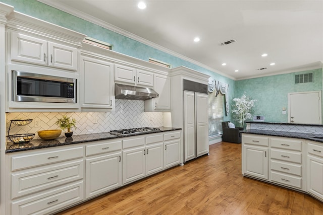 kitchen featuring under cabinet range hood, visible vents, appliances with stainless steel finishes, and ornamental molding