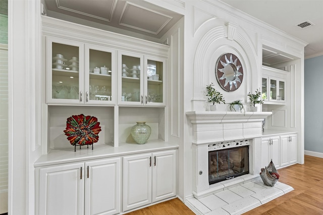 details featuring wood finished floors, visible vents, baseboards, a fireplace, and crown molding