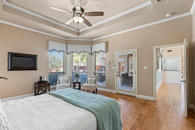 bedroom featuring access to exterior, light wood finished floors, a raised ceiling, and crown molding