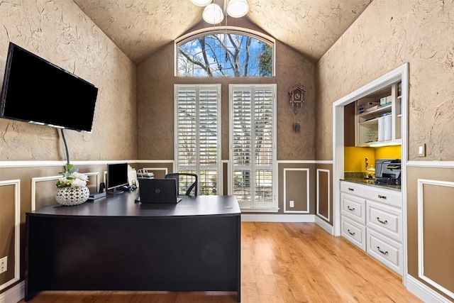 office space featuring wainscoting, light wood-style flooring, and lofted ceiling