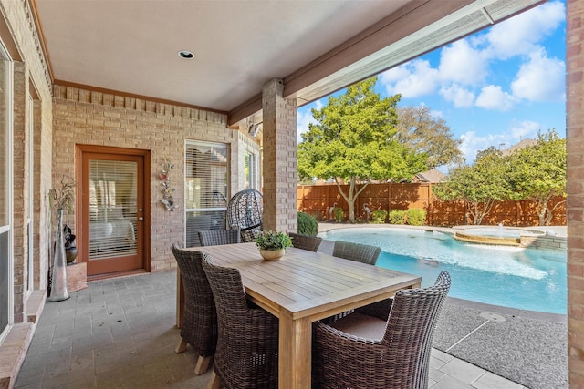 view of patio / terrace with outdoor dining space, a pool with connected hot tub, and a fenced backyard