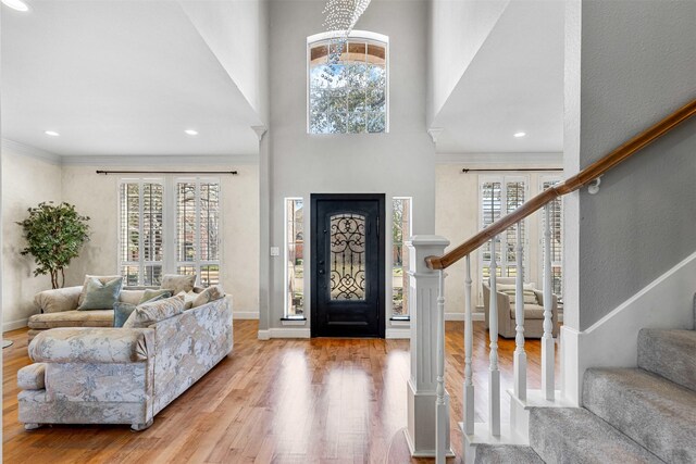 foyer with stairway, wood finished floors, baseboards, a towering ceiling, and crown molding