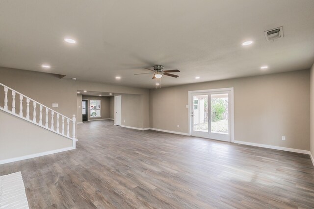 unfurnished living room featuring visible vents, wood finished floors, recessed lighting, stairway, and baseboards