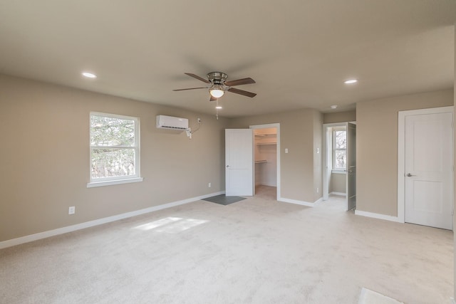 unfurnished bedroom featuring a wall unit AC, recessed lighting, light colored carpet, and baseboards