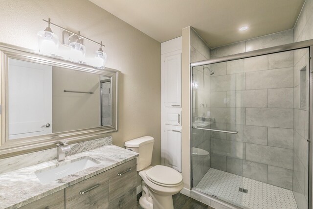 full bathroom with toilet, a stall shower, and vanity