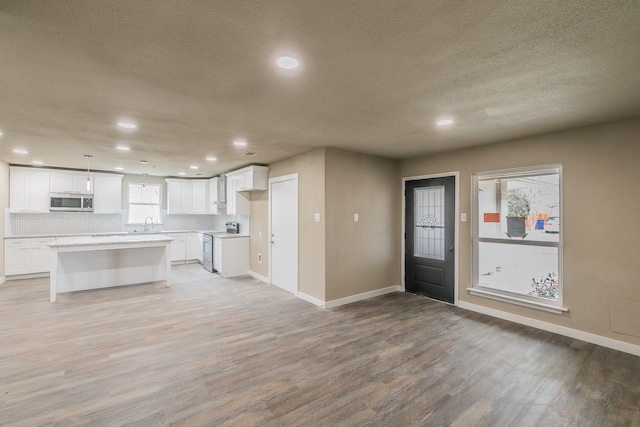 kitchen with electric range, light countertops, light wood-style floors, white cabinetry, and stainless steel microwave