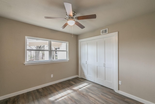 unfurnished bedroom featuring visible vents, baseboards, a closet, and wood finished floors