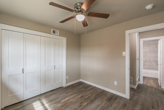 unfurnished bedroom with a closet, baseboards, dark wood-type flooring, and visible vents