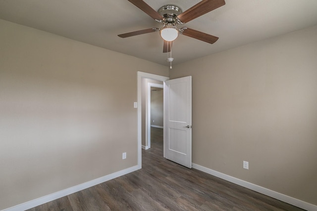 empty room featuring dark wood-style floors, a ceiling fan, and baseboards