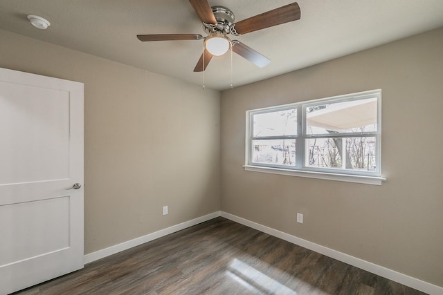 unfurnished room featuring baseboards, a ceiling fan, and dark wood-style flooring