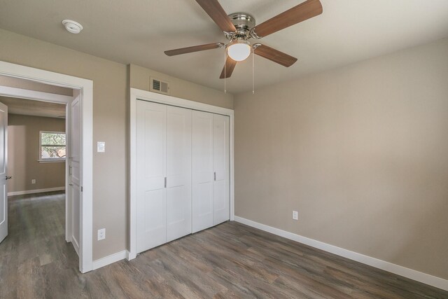 unfurnished bedroom featuring dark wood finished floors, visible vents, a closet, and baseboards