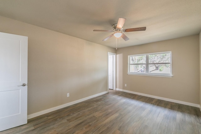 empty room with a ceiling fan, dark wood-style floors, and baseboards