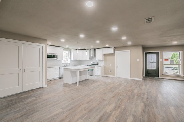 kitchen with visible vents, stainless steel appliances, white cabinetry, wall chimney exhaust hood, and light wood-type flooring