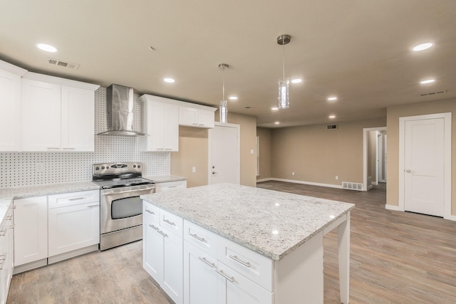 kitchen featuring wall chimney range hood, stainless steel range with electric stovetop, visible vents, and light wood-type flooring