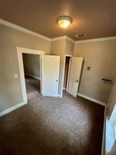 unfurnished bedroom featuring dark carpet, crown molding, and baseboards