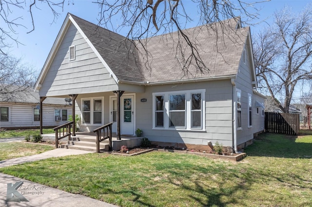 view of front of property featuring a front lawn, fence, and a shingled roof