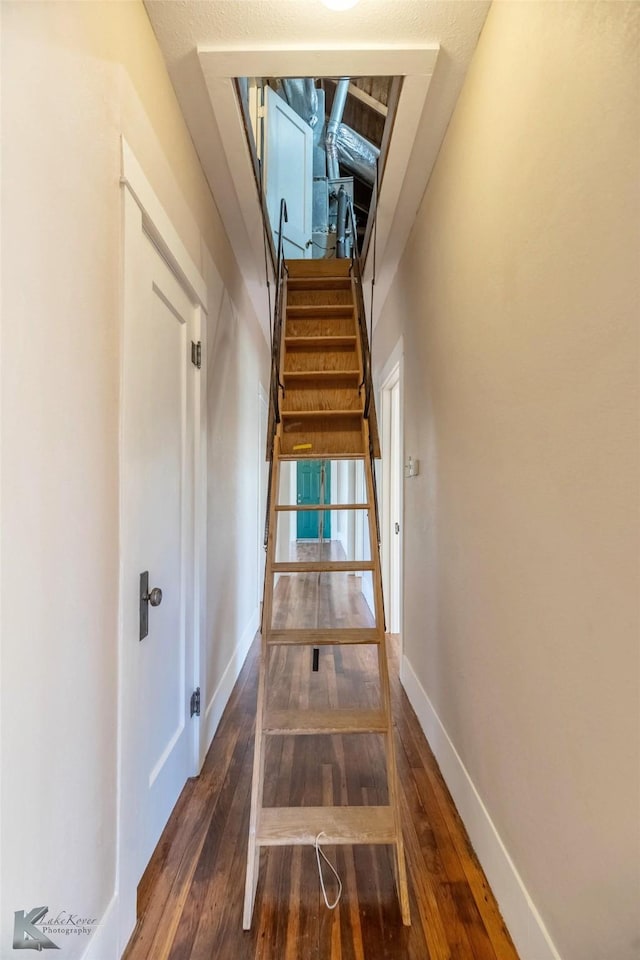 hall with stairs, baseboards, and wood finished floors