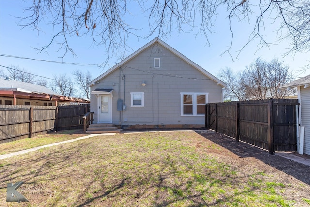 back of house featuring entry steps, a fenced backyard, and a lawn