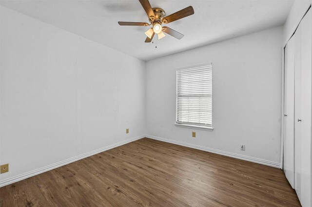 unfurnished bedroom with a closet, a ceiling fan, baseboards, and wood finished floors