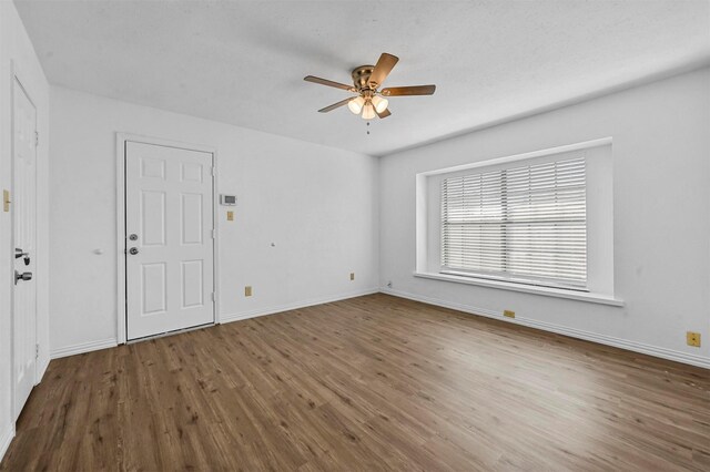 spare room with baseboards, ceiling fan, and wood finished floors