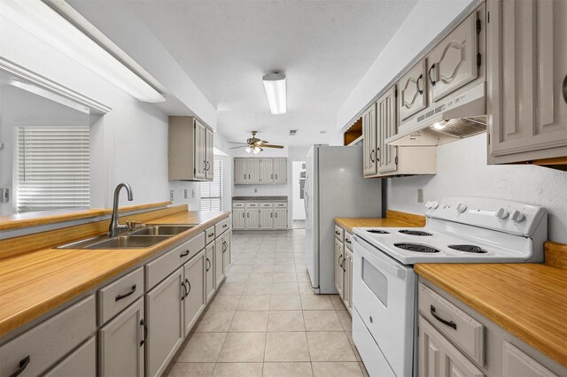 kitchen with white appliances, light tile patterned floors, a sink, light countertops, and under cabinet range hood