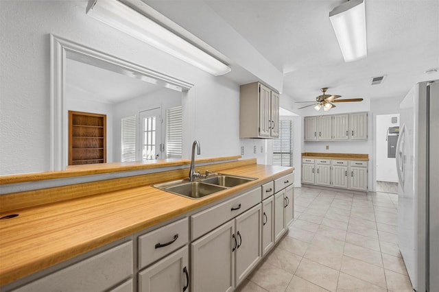 kitchen with visible vents, light countertops, light tile patterned floors, freestanding refrigerator, and a sink