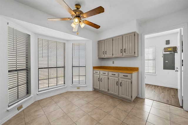 kitchen with a ceiling fan, cream cabinets, light countertops, light tile patterned floors, and baseboards