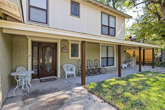 doorway to property with a porch and brick siding