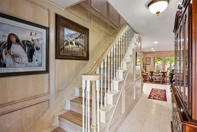 stairs with tile patterned floors, a textured ceiling, and a decorative wall