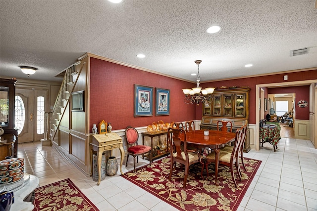 dining room with visible vents, a chandelier, stairway, light tile patterned floors, and a decorative wall