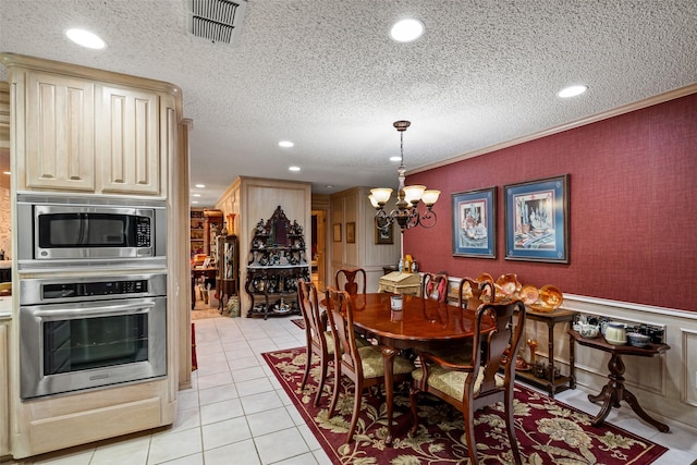 dining room with visible vents, a textured ceiling, an inviting chandelier, light tile patterned flooring, and wallpapered walls