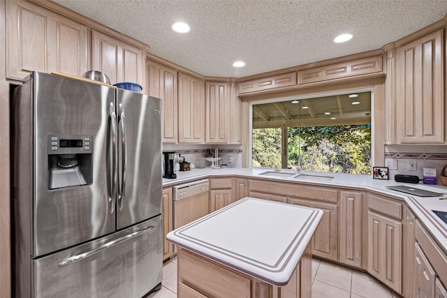 kitchen featuring stainless steel fridge with ice dispenser, light brown cabinetry, light countertops, light tile patterned floors, and a sink