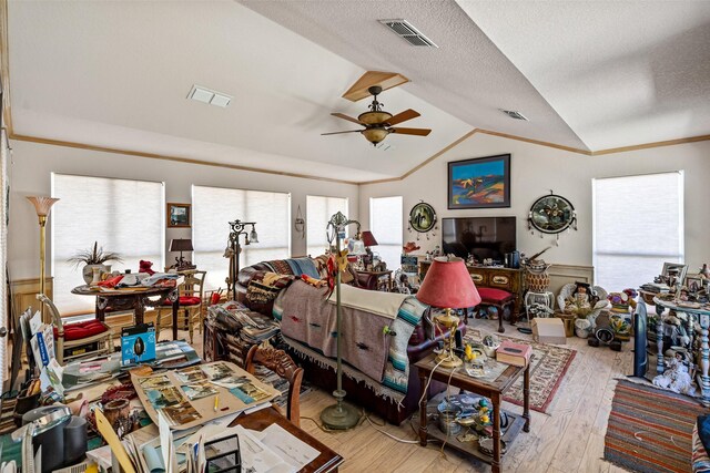 living area featuring a wainscoted wall, vaulted ceiling, wood finished floors, and visible vents