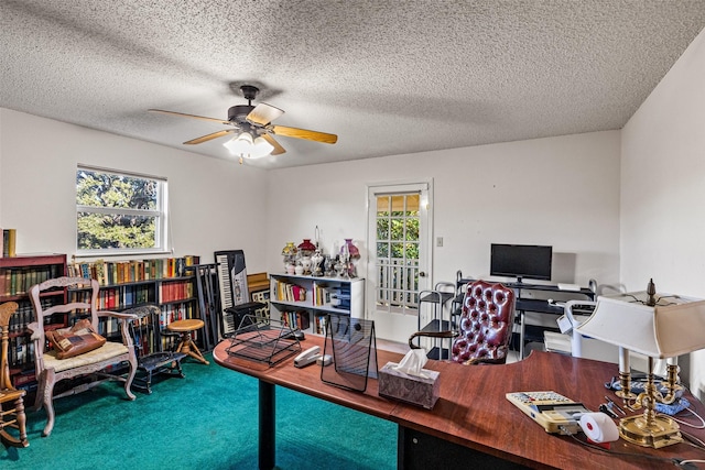 home office with a textured ceiling, a healthy amount of sunlight, carpet floors, and ceiling fan