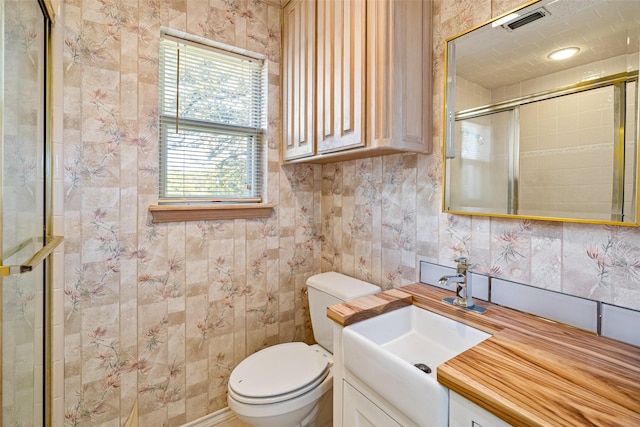 bathroom with visible vents, toilet, vanity, and a tile shower