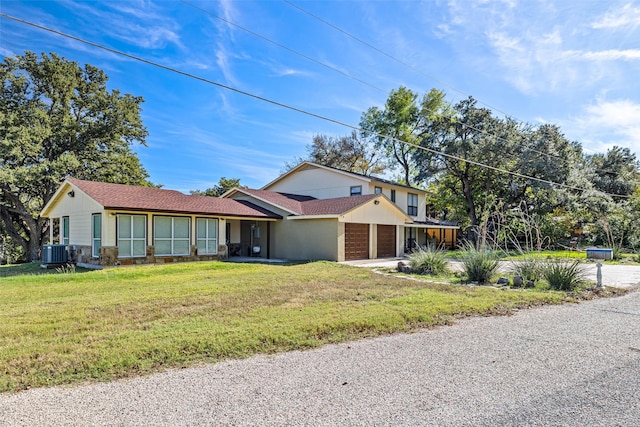 view of front of house featuring a front yard, central air condition unit, concrete driveway, and a garage