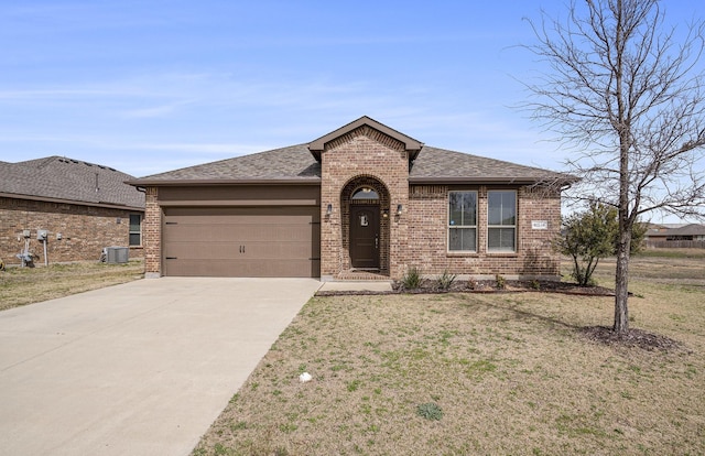 view of front of house featuring a front yard, driveway, roof with shingles, a garage, and brick siding