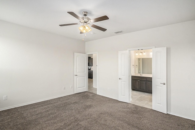 unfurnished bedroom featuring a ceiling fan, baseboards, visible vents, light colored carpet, and connected bathroom