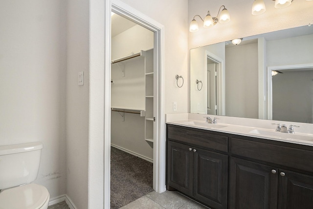 full bath featuring double vanity, a sink, tile patterned flooring, a spacious closet, and toilet