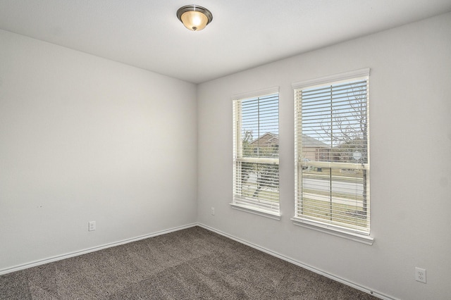 empty room featuring baseboards and dark carpet