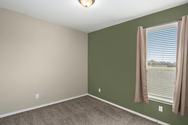 unfurnished room featuring baseboards and dark colored carpet