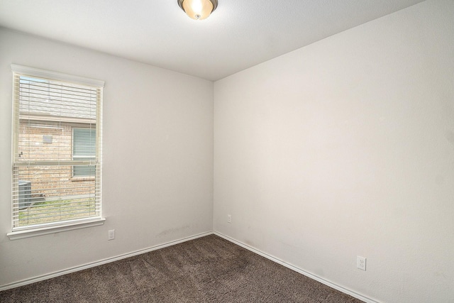 unfurnished room with dark carpet and baseboards