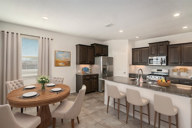 kitchen with visible vents, a sink, appliances with stainless steel finishes, decorative backsplash, and dark brown cabinets