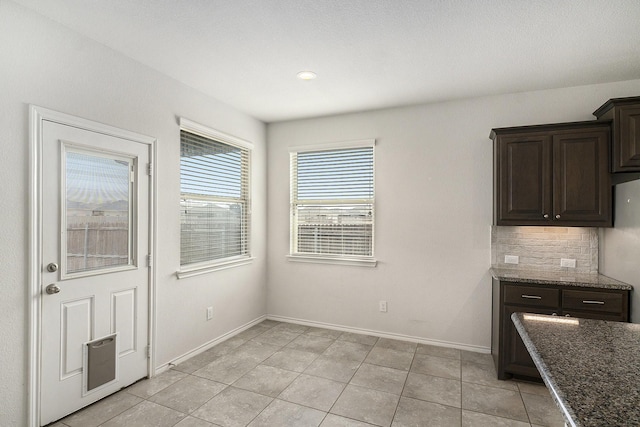 unfurnished dining area featuring light tile patterned floors and baseboards