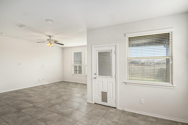 spare room with tile patterned flooring, baseboards, visible vents, and ceiling fan