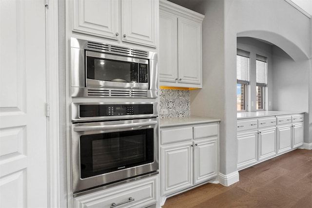 kitchen featuring backsplash, light countertops, wood finished floors, white cabinets, and stainless steel appliances