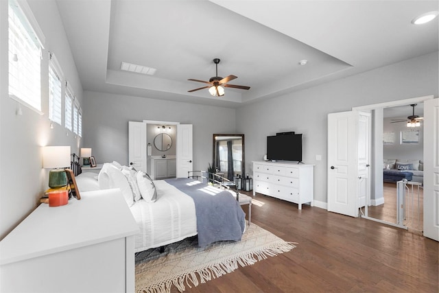 bedroom featuring visible vents, a raised ceiling, a ceiling fan, baseboards, and dark wood-style flooring